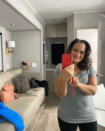 Picture of Tracy Vilar holding a phone and taking mirror selfie herself. 